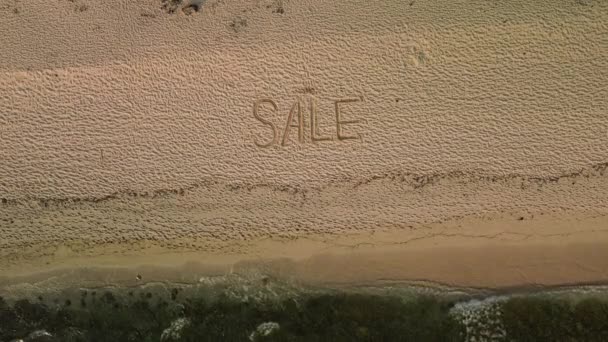 海滩的空中景观 上面有出售的铭文在沙滩上 黑色星期五大甩卖背景视频 背景音乐录影带 在沙地上出售题词 — 图库视频影像
