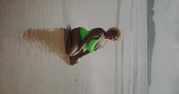 アフリカ系アメリカ人の若い女性の垂直ビデオは 海岸の水着で分裂しています ストレッチとアクティブなライフスタイル 身体のポジティブさと自分自身の受け入れ — ストック動画