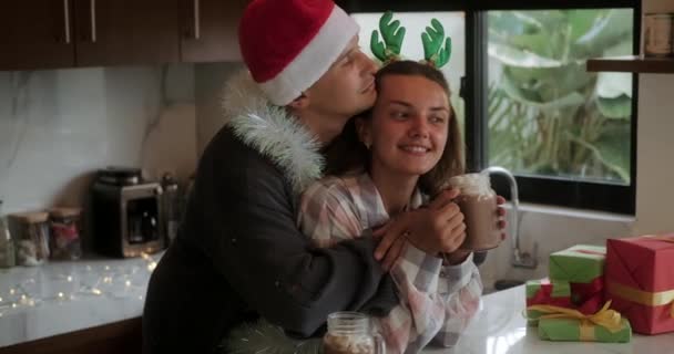 Een Man Met Een Kerstmuts Knuffelt Kust Een Jonge Vrouw — Stockvideo