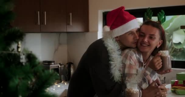 和心爱的人在一起的圣诞家庭传统一对穿着圣诞服装的情侣在厨房拥抱 用棉花糖喝可可 温馨的新年在家庭圈 — 图库视频影像