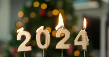 Yeni yıl arka planında mumlardaki yangını söndürme videosu 2024 yılına ait. Ateş söner ve mumlar düşer. Işıklı bir Noel ağacının arka planına..