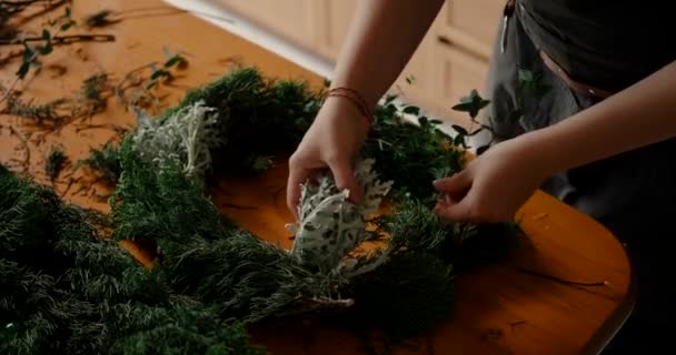 여자의 가루와 소나무 가지의 조성을하고 그들로부터 크리스마스 화환을 만듭니다 크리스마스 — 비디오