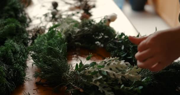 クリスマスリースや装飾品を生産する小規模ビジネス 若い女性の手は 果実やコーンの形で花の枝や装飾の羽を作成します Diyの休日の装飾 — ストック動画