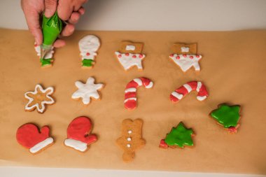 Adam elinde içinde yeşil krema olan bir pasta torbası tutuyor. Noel için zencefilli kurabiye pişirir. Kar tanesi, kardan adam ve Noel ağacı şeklinde kurabiyeler..