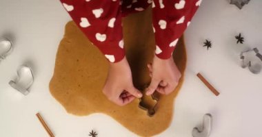 Genç bir kadın tarafından yapılan zencefilli kurabiyelerle dolu bir masanın üst görüntüsü. Kurabiye keskisi ve hamur masada. Zencefilli kurabiye adam, Noel ağacı ve kar tanesi..