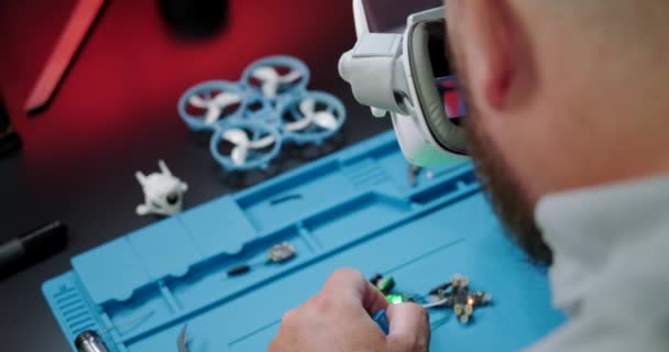 一名正在修理Fpv无人机的男性工程师的特写 他把无人机的眼镜拿到脸上 检查连接情况 将设备维修作为一项业余爱好 — 图库视频影像