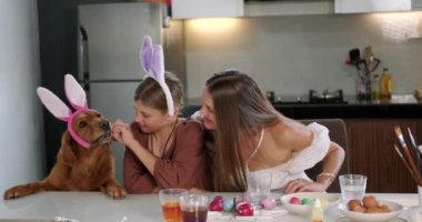 Paskalya Anne ve Kızı 'nın aile gelenekleri masaya oturup yanında tavşan kulaklı bir av köpeği olan Paskalya yumurtalarını süslemektir. Hıristiyan bayramı.
