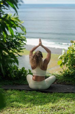 Lotus pozisyonunda bir uçurumun kenarında oturan kıvırcık saçlı genç bir kadının arkasından okyanusa bakar ve meditasyon yapar. Doğada huzur, sessizlik ve sükunet..