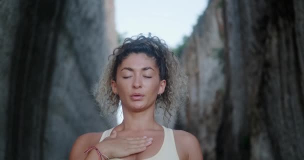 一个有着卷发的年轻拉美女人在白色岩石的背景下做呼吸练习的肖像 她闭上眼睛深深地吸了一口气 冥想与和平的概念 精神健康 — 图库视频影像