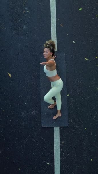一个有着卷发的年轻拉美女人 从上到下都在铺着石头的路上做瑜伽 她表演着风琴 微笑着 高瞻远瞩 垂直录像 — 图库视频影像