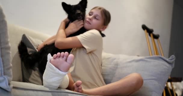 Ein Junges Mädchen Mit Einem Gips Bein Sitzt Wohnzimmer Auf — Stockvideo