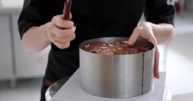 Tereyağlı kremalı ve ahududu reçelli çikolatalı pastadan pastayı çıkaran genç bir pasta şefinin yakın çekimi. Profesyonel bir mutfakta işlem.