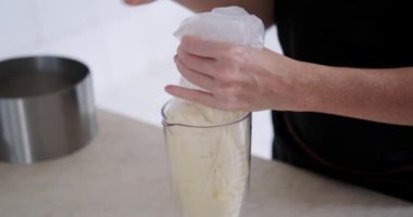 Genç bir pasta şefinin ellerinin yakın çekimi. Bir restoranın mutfağında pasta için krema hazırlıyor. İçinde tereyağı olan bir pasta torbasını çeviriyor. Tatlıyı hazırlama süreci.