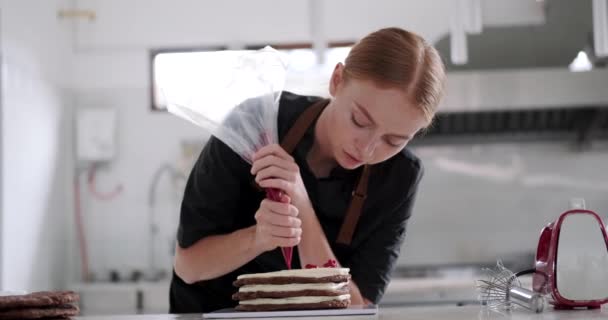 Портрет Молодой Рыжеволосой Кондитерши Наносящей Масляный Крем Слой Шоколадного Торта — стоковое видео