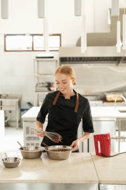 Masaya un serpiştirilmiş çikolata hamuru yoğuran kızıl saçlı genç bir pasta şefinin portresi. Bir şekerleme dükkanında çikolatalı pasta hazırlama süreci.