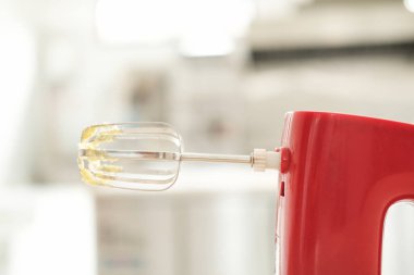 Pastane ve pastane için arka plan afişi. Masanın üzerinde biraz tereyağı kreması kalmış kırmızı bir mikser var. Arka planda bir şekerleme dükkanının yapım atölyesi var..