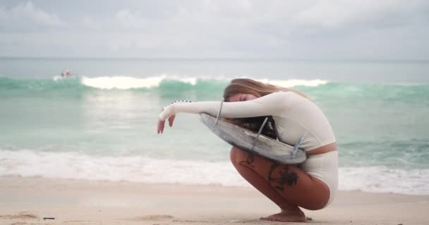 Young Blonde Woman White Surf Bikini Sitting Beach Surfboard Looking — Stock Video