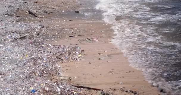 沙滩被塑料垃圾污染了 全球环境灾难 海滩上堆积如山的垃圾来自海洋 废物在水里漂浮 避免使用塑料袋和塑料瓶 — 图库视频影像