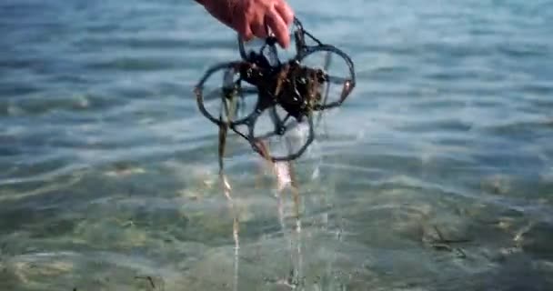 Fpvドローンを海の水から取り出し 藻類を取り除き それを水から揺さぶる男の手 ドローン クラッシュ — ストック動画