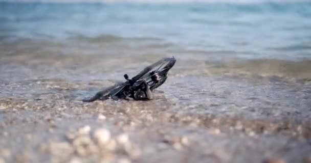 一个Fpv无人机的特写镜头 它躺在海面上的水里 在海滩上发现一架无人机信号丢失和故障无人机坠毁 — 图库视频影像