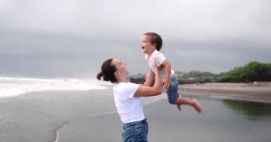 Okyanus kıyısında tatildeyken küçük oğlunu kollarında tutan bir annenin arka görüntüsü. Küçük çocuk gülüyor. Tatillerde neşeli aile anları. Anneler Günü.