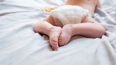 Beyaz bezli, açık gri battaniyeli şirin bir bebeğin üst görüntüsü. Pankart formatı, Anneler Günü. Bebek bezi değiştirip bebek derisine iyi bak. Boşluğu kopyala. 