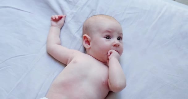 Bebê Está Deitado Cobertor Leve Olha Para Cima Mastiga Dedos — Vídeo de Stock