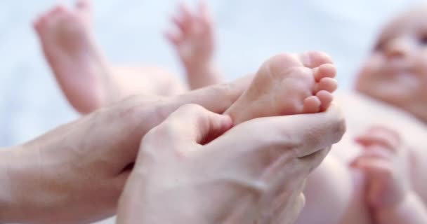 生まれたばかりの赤ん坊の足をストローキングする母親の手を閉じます ベビーケア フットマッサージ 娘の健康と世話をする マザーズ 小児科医 マニュアルマッサージを改善する健康 — ストック動画