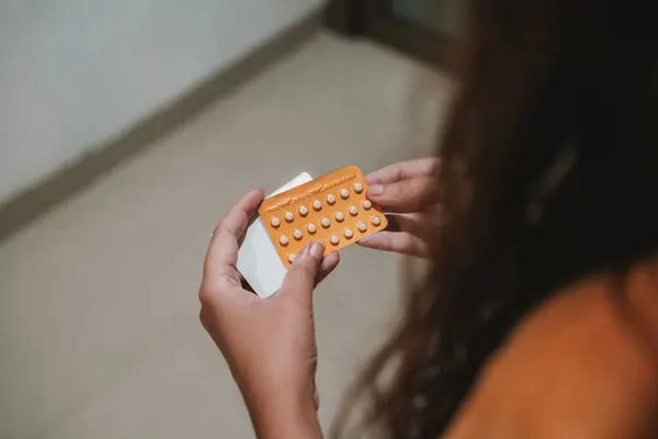 stock image Back view of the hands of a young woman holding a pack of birth control pills. Contraceptive pills. Birth control. Childfree.