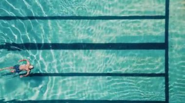 Sırtüstü uzanmış mavi suyla havuzda yüzen bir adamın en iyi görüntüsü. Tatilde olan bir turist aktif spor ve sağlık hizmetlerine katılır. Tatilde bir tatil beldesinde dinlenme.