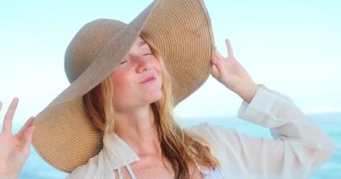 Mavi okyanus kıyısında sahilde yürüyen, saman şapkalı çilli genç kızıl saçlı bir kadının portresi şapkasını düzeltirken güneşe ve şaşılara bakıyor. Yaz tatili.