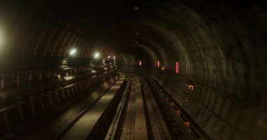 Ağır çekimde, bir trenin geçtiği metro tünelinin manzarası. Karanlık yuvarlak tünel parlak fenerler ve yer altındaki kıvrımlarla aydınlatılır. Büyük bir şehirde metro. Sinematik ulaşım yolu.
