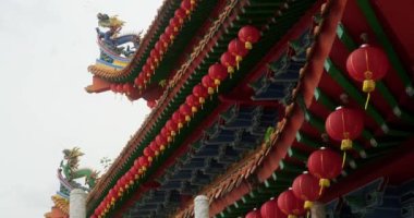 Bir Çin tapınağının çatısını ve gökyüzüne karşı asılı kırmızı kağıt fenerleri. Çatıda ejderha heykelleri var. Çin Yeni Yılı. Doğu renkli din. Budizm.