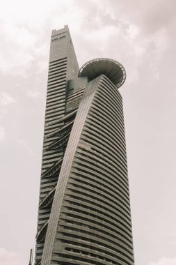 Yansıtıcı panellerle kaplı yüksek bir gökdelenin dipteki görüntüsü. Malezya 'nın Kuala Lumpur kentindeki modern binalar. Güneydoğu Asya 'nın başkenti. İş merkezi.