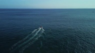 Okyanusun ortasında bir kayığa tutunurken folyo üzerinde uçan bir adamın görüntüsü. Yeni bir ekstrem spor türü. Gelecekçi modern sörf tahtası.