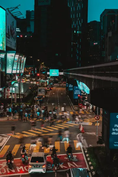 stock image Busy Bukit Bintang street Kuala Lumpur, Malaysia. Many people are crossing the road. The car is waiting for the green light of the traffic light. The street is lit with neon and looks futuristic.