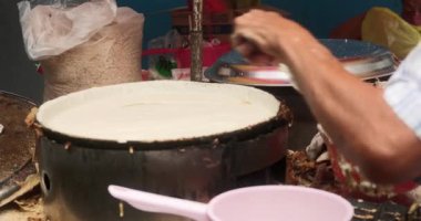 Çin Mahallesi, Kuala Lumpur, Malezya 'da sokak yemekleri. Hamuru kızartma tavasına dağıtan ve krep pişiren yaşlı bir adamın yakın çekimi. Tatlı sokak yemekleri.