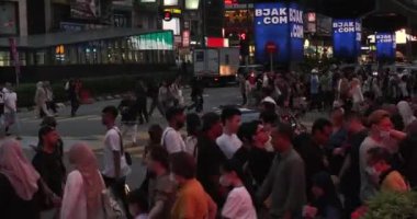 Meşgul Bukit Bintang Caddesi Kuala Lumpur, Malezya. Birçok insan karşıdan karşıya geçiyor. Araba trafik lambasının yeşil yanmasını bekliyor. Sokak neon ışıklarıyla aydınlatılmış ve fütüristik görünüyor..