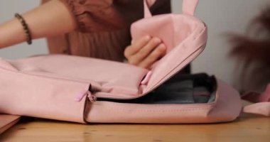 Sınıfa gitmek için okul çantasını hazırlayan genç bir kızın ellerini yakın plan çekeceğiz. Sırt çantasına defter, kalem kutusu, dizüstü bilgisayar ve diğer kırtasiye malzemelerini koyuyor. Okula geri dön..