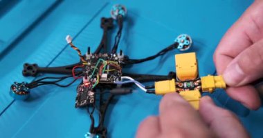 Erkek mühendislerin ellerini masasındaki FPV insansız hava aracını tamir ederken kapatın ve sinyal gelene kadar çalıştırın. Ekipman onarım ve bakım servisi merkezi. Drone onarımı.