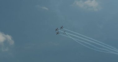 Bir hava gösterisinin yapıldığı mavi gökyüzünün altından görüntüyü al. Bir grup askeri uçak inanılmaz numaralar sergiliyor. Uçağın arkasında bir buhar şeridi var. Profesyonellerin aşırısı.