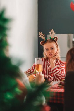 Saçında geyik boynuzu olan kızıl saçlı genç bir kadın Noel yemeğinde arkadaşlarıyla masada oturuyor. Konuşuyorlar ve şampanya içiyorlar. Yakın insanlarla evde tatil yapmak. Yeni Yıl.