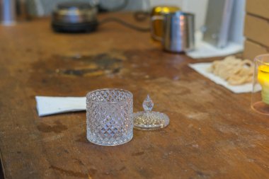 Mum yapma atölyesindeki atölye manzarası. Masanın üzerinde boş bir cam mum kabı var. Arka planda aromatik yağlı kavanozlar, filizler, kutular. Evde yaratıcı çalışma süreci..