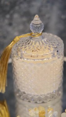 Dekoratif bardakta sarı püsküllü bir mumun yakın çekimi. Ürün sunumu için özel bir stantta dönüyor. El yapımı mum tasarımı.