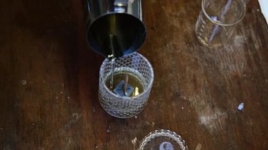 Kadın ellerinin erimiş balmumunu demir bir kaseden gelen aromatik yağla cam bir mum kalıbına dökmesini. Ev yapımı mum yapımı bir atölyede. Küçük yaratıcı iş.