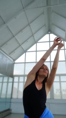 Parlak bir stüdyoda çağdaş bir dans gösterisi sırasında zarif bir şekilde kollarını ve başını hareket ettiren bir kadın dansçının yakın plan portresi. Onun ifadesi tutku ve zarafeti yansıtır..