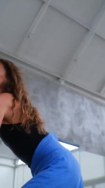 Parlak bir minimalist stüdyoda enerjik ve güçlü bir çağdaş dans gösterisi yapan bir kadın dansçının orta boy fotoğrafı. Hareketleri dinamik ve güç dolu..