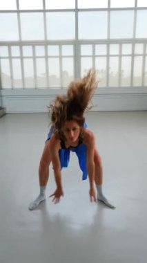 Parlak bir stüdyoda şehvetli çağdaş bir dans sergileyen bir kadının orta ölçekli görüntüsü. Hareketleri etkileyici. İzleyiciyi büyülerken kendine güvenini ve zarifliğini vurguluyor..