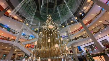 Güzel bir tatil süslemesi manzarası ve çok katlı bir sıra insan onlarla yürüyor. Büyük Pavilion KL alışveriş merkezi, Kuala Lumpur, Malezya - 25 Aralık 2024