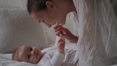 Büyüleyici bir bebek, annesinin yanındaki beyaz bir battaniyenin üzerinde uzanmış, ona gülümseyen, onunla konuşan ve onu şefkatle öpen genç bir kadındır. Anne ve kızı. Sevgi ve ilgi. Anneler Günü